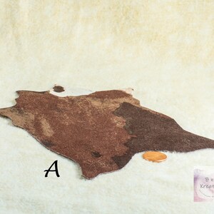 Shows a miniature cowskin rug in shades of brown and white. The rug is irregularly shaped, with a textured appearance. The letter "A" is printed near the rug. The rug is a dollhouse miniature. It is on a biege background with a penny to show scale.
They are made for 1:12 scale or 1:6 scale miniature dollhouses or diorama scenes and are not full sized.