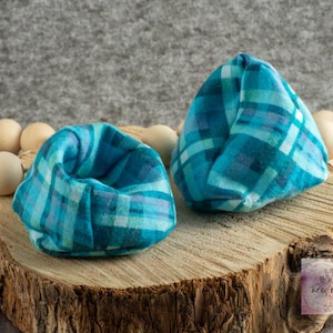 May include: Two teal blue fabric pouches with a plaid pattern. The pouches are sitting on a wooden surface.