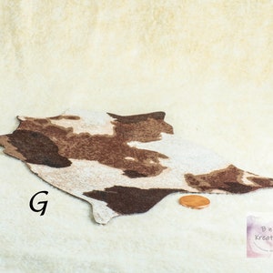 Shows a miniature cowskin style rug in browns and cream. It is on a biege background. The letter G is to the side of the rug. A penny is in front of the rug to show scale.
They are made for 1:12 scale or 1:6 scale miniature dollhouses or diorama scenes and are not full sized.