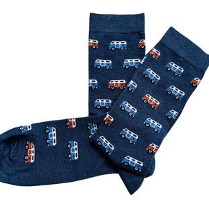 May include: Navy blue socks featuring a repeating pattern of miniature camper vans in red, white, and blue. The socks are made from a soft, knitted material and are designed for wear on the feet.