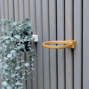 Puede incluir: Una taza de cerámica blanca con asa negra y el texto "But First, Coffee" en negrita negra. La taza se encuentra sobre un fondo borroso, sugiriendo un ambiente acogedor.