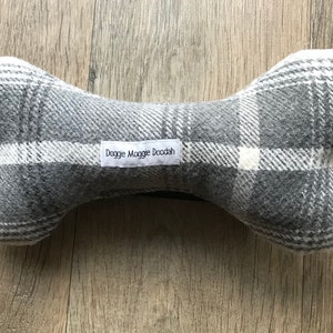 May include: A grey and white plaid dog bone toy with the text "Doggie Moggie Doodah" on the label.