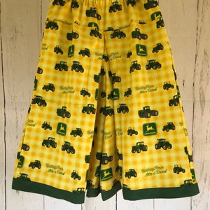 May include: Yellow and white plaid pants with a green trim. The pants are patterned with green tractors and the John Deere logo. The text "Nothing Runs Like a Deere!" is also printed on the pants.