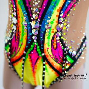 Pu&ograve; includere: Primo piano di un body colorato con un design arcobaleno e strass. Il body &egrave; realizzato in tessuto elastico a rete e ha un bordo nero. Il body &egrave; stato disegnato da @leo_leotard di Natly Zrazhevska.