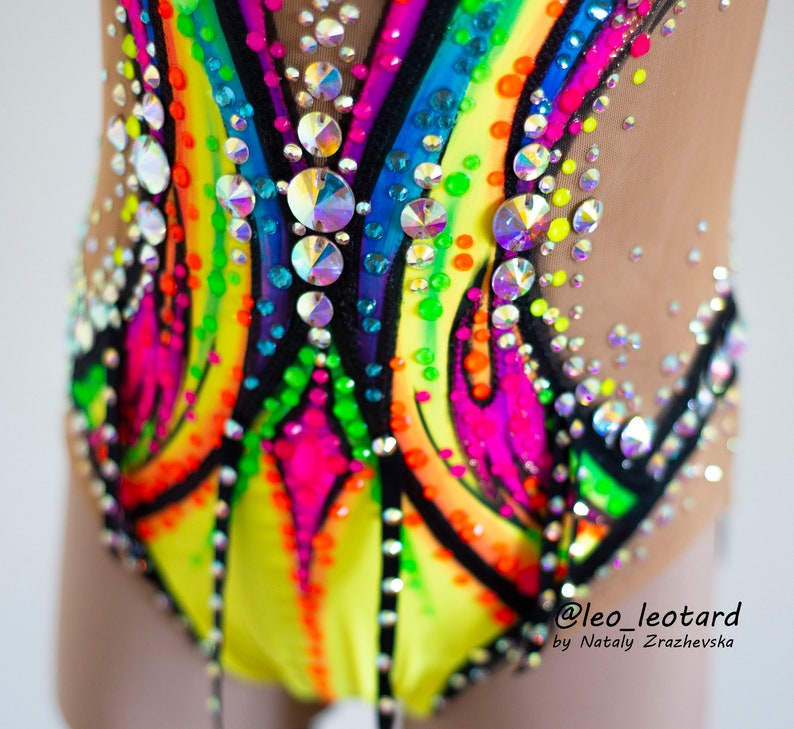 Pu&ograve; includere: Primo piano di un body colorato con un design arcobaleno e strass. Il body &egrave; realizzato in tessuto elastico a rete e ha un bordo nero. Il body &egrave; stato disegnato da @leo_leotard di Natly Zrazhevska.