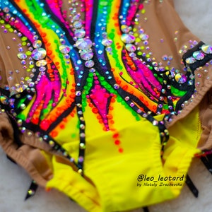 Pu&ograve; includere: Un body giallo con un design arcobaleno e accenti neri. Il body &egrave; decorato con strass e ha un'overlay in rete. Il body &egrave; realizzato da @leo_leotard di Natay Zrazhevska.