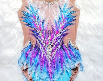 May include: A nude-colored leotard with a vibrant design featuring blue, purple, and pink accents. The leotard is embellished with sparkling rhinestones and has a flowing, layered skirt. This garment is designed for gymnastics or dance performances.