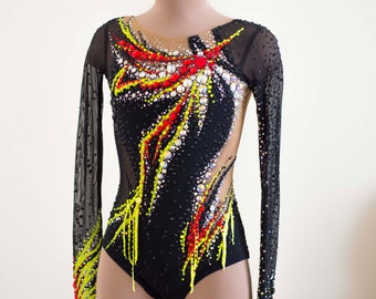 May include: Black leotard with long sleeves and a colorful design featuring yellow, red, and black accents. The leotard is decorated with rhinestones.