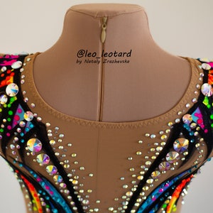 Pu&ograve; includere: Un body color carne con un design a arcobaleno e accenti neri. Il body &egrave; decorato con strass e ha una cerniera sul retro. Il testo "@leo_leotard by Nataly  Zrazhevksa" &egrave; stampato sul retro.
