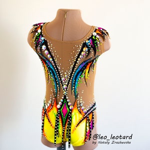 Pu&ograve; includere: Un body giallo, nero e arcobaleno con strass. Il body ha una schiena trasparente e un design colorato. Il body &egrave; su un manichino. @leo_leotard by Nataliy  Zrazhevksa