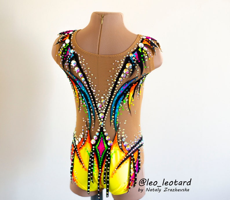 Pu&ograve; includere: Un body giallo, nero e arcobaleno con strass. Il body ha una schiena trasparente e un design colorato. Il body &egrave; su un manichino. @leo_leotard by Nataliy  Zrazhevksa