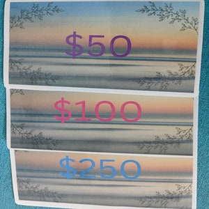 Puede incluir: Tres certificados de regalo con un fondo de acuarela de una puesta de sol sobre el océano. Los certificados son por 50 €, 100 € y 250 €.