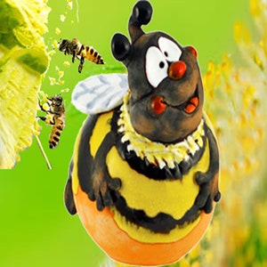 Könnte beinhalten: Eine Keramik-Bienenfigur mit einem gelb-schwarz gestreiften Körper, braunem Kopf und großen, kulleraugen. Die Biene lächelt und hat eine rote Zunge herausgestreckt. Die Figur sitzt auf einem grünen Hintergrund.