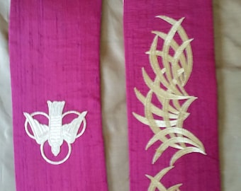 May include: Two pink fabric stoles with gold embroidery. One stole features a white dove with a halo, the other features a stylized gold thorn design.