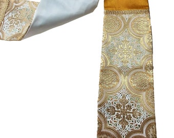 May include: A white and gold liturgical stole with a gold fringe. The stole has a white background with a gold pattern of circles and crosses.