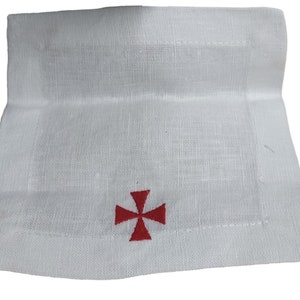 May include: White linen napkin with a red embroidered cross.