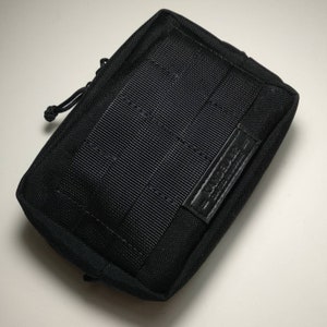 Puede incluir: Bolsa negra con cremallera, exterior de tejido texturizado y etiqueta negra que dice "5.11 Tactical"