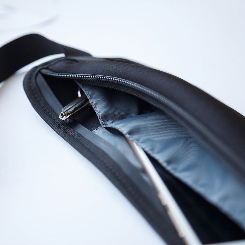 May include: A black zippered pouch with a gray lining. A silver key is visible inside the pouch.