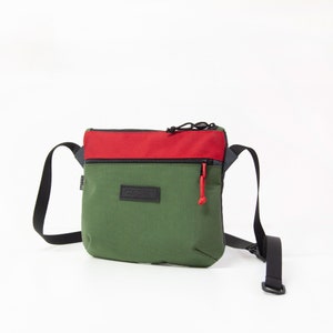 May include: A green and red crossbody bag with a black zipper and a black label that says "CHROME" on it.