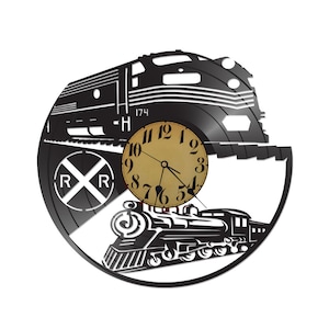 May include: Black wall clock with a train design cut from a vinyl record. The clock face is tan with black numbers and hands. The design includes a train, railroad tracks, and the letters "R" and "R" in a circle. The number "174" is also visible.