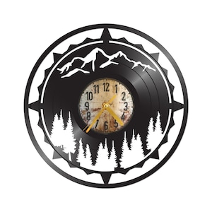 May include: Black vinyl record clock with a white silhouette of a mountain range and pine trees. The clock face is a vintage-style, cream-colored clock with black numbers and gold hands.