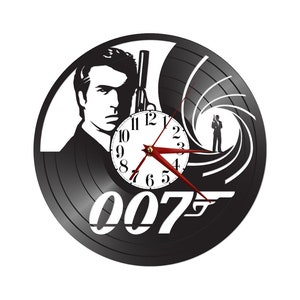 以下が含まれることがあります： ジェームズ・ボンドが銃を持っているシルエット、象徴的な007のロゴ、そして中央に時計の文字盤が描かれた黒いレコードの時計です。
