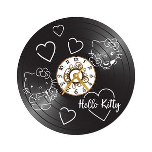 May include: Black vinyl record clock featuring Hello Kitty designs and hearts. The clock face has gold hands and a decorative border. The words "Hello Kitty" are written in white script on the record.