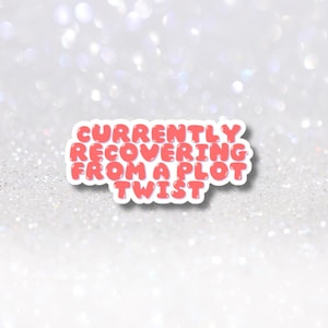 May include: A sticker with the text "CURRENTLY RECOVERING FROM A PLOT TWIST" in a bubble font. The text is in a coral color with a white outline. The sticker is on a sparkly, glittery background.