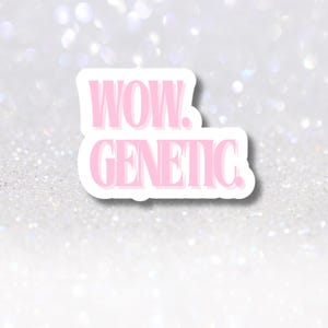 以下が含まれることがあります： 「WOW. GENETIC.」という言葉が太字のサンセリフ体で書かれたピンク色のステッカー。ステッカーは白い縁取りがあり、キラキラ光る銀色の背景に配置されています。