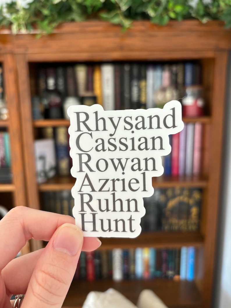 Puede incluir: Una pegatina blanca con los nombres Rhysand, Cassian, Rowan, Azriel, Ruhn y Hunt escritos en texto negro.