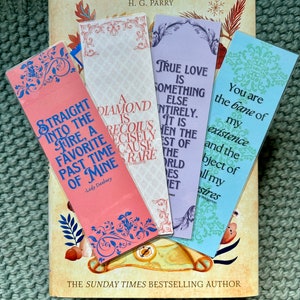 May include: Four colorful bookmarks with inspirational quotes. The quotes are: "Straight into the fire, a favorite past time of mine" - Lady Danbury, "A diamond is precious, precisely because it is rare", "True love is something else entirely. It is when the best of the world does meet", "You are the bane of my existence and the object of all my desires".