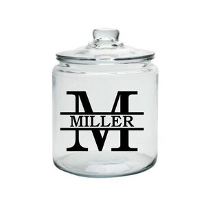 May include: A clear glass jar with a lid, featuring a black vinyl decal with the letter "M" and the name "MILLER" centered below the letter.