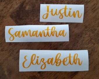May include: Three white labels with gold lettering. The labels read "Justin", "Samantha", and "Elizabeth".