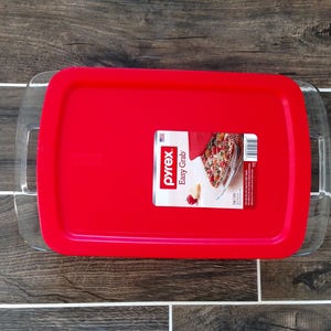 May include: A red Pyrex Easy Grab baking dish with a clear glass lid. The lid has handles on the sides. The dish has a label that says "Pyrex Easy Grab".
