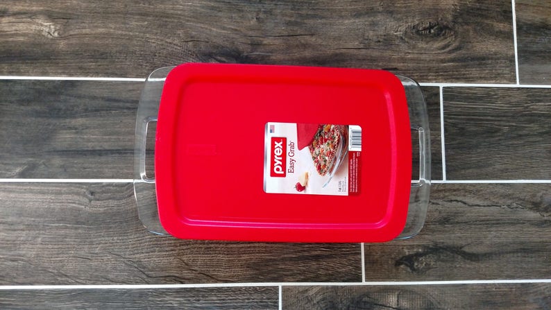 May include: A red Pyrex Easy Grab baking dish with a clear glass lid. The lid has handles on the sides. The dish has a label that says "Pyrex Easy Grab".