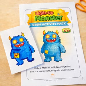 May include: A STEM activity pack titled "Light-Up Monster" featuring a blue monster illustration with glowing eyes. The pack includes a smaller card with a similar monster design. The text reads "Make a Monster with Glowing Eyes!" and "Learn about circuits, magnets and switches."