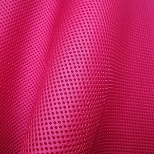 May include: Close-up of a bright pink mesh fabric with a repeating pattern of small holes. The fabric is textured and has a slight sheen.