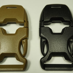 Puede incluir: Dos hebillas de plástico, una de color marrón oscuro y la otra negra. Ambas hebillas tienen un diseño similar con una forma rectangular y una abertura central.