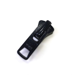 May include: Black plastic zipper pull with a rectangular shape and a small opening in the center. The pull has a raised, textured surface.