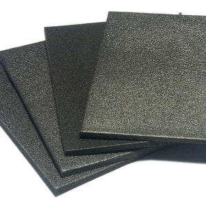 Puede incluir: Cuatro piezas rectangulares de aislamiento de espuma negra apiladas una encima de la otra.