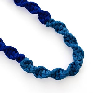 Puede incluir: Un collar trenzado azul y turquesa con un cierre plateado.