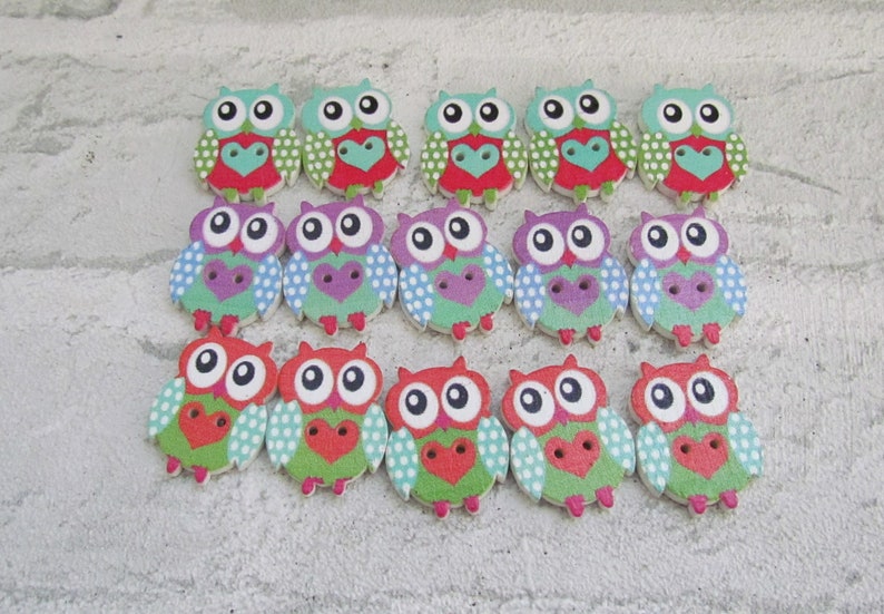 May include: A set of 18 wooden owl buttons in various colors, including green, red, blue, and purple. Each button features a white polka dot pattern and a heart design.