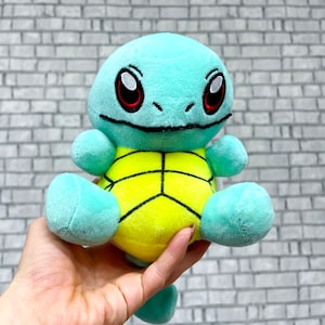 May include: A plush toy of a blue and yellow turtle with a shell. The turtle has a friendly face with big eyes and a small mouth.
