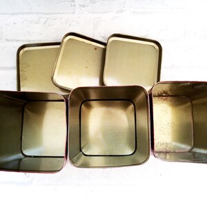 May include: Set of five vintage metal storage containers with red trim. The containers are empty and have a gold interior.