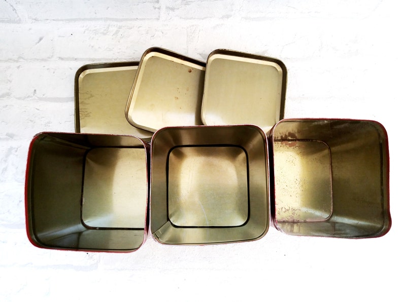 May include: Set of five vintage metal storage containers with red trim. The containers are empty and have a gold interior.