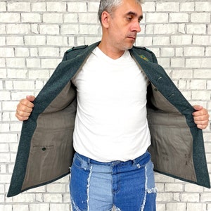 May include: A dark green jacket with a brown lining. The jacket has a pocket on the inside and a label with the text "50 69" on the inside. The jacket is open and a person is wearing it.