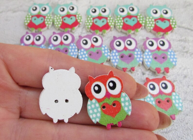 May include: Assortment of wooden owl buttons with various colorful patterns. Some buttons are plain white. The buttons are approximately 2 inches in diameter.