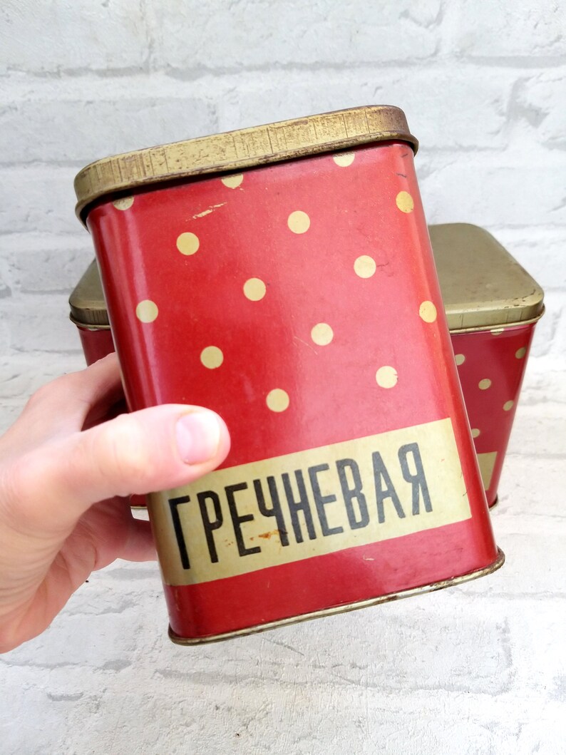May include: Red metal storage container with white polka dots and the word "ГРЕЧНЕВАЯ" in gold lettering.