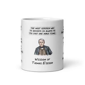 May include: A white ceramic mug featuring a color illustration of Thomas Edison wearing a suit and bowtie. Above the portrait is the text, The most certain way to succeed is always to try just one more time. Below is Wisdom of Thomas Edison.