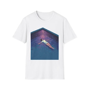 May include: White t-shirt featuring a graphic of a person floating in a pool. The pool is a deep blue with a purple and pink sky above. The person is wearing a white shirt and shorts.
